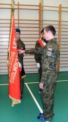 "Kadet" w mundurze i klapkach ślubujący na sztandar 