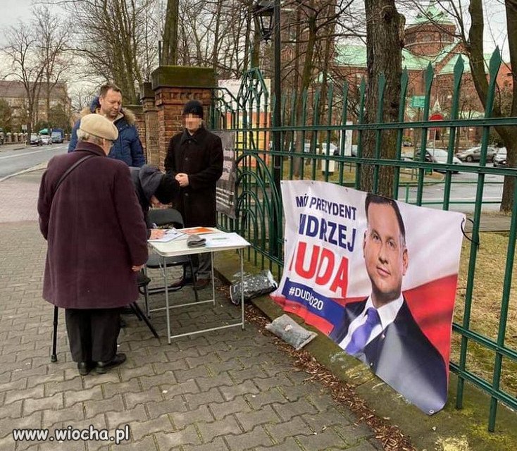 Baner z prezydentem na kościelnym ogrodzeniu.